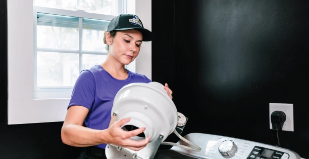 A residential booster fan installation taking place by Dryer Vent Wizard pro in a laundry room.
