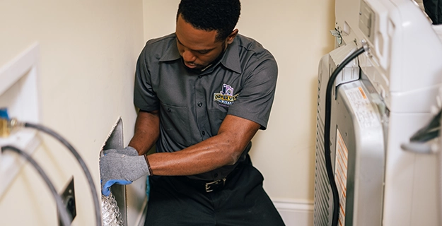 Technician kneeling to replace dryer duct.