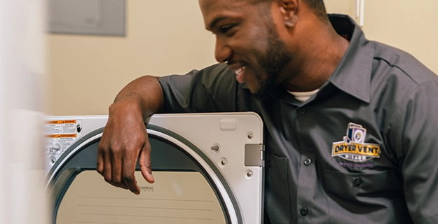 Technician standing beside an open dryer door.