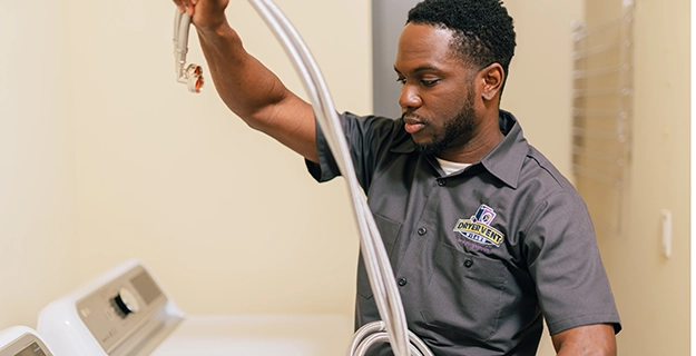 Tech working on washing machine hose replacement.