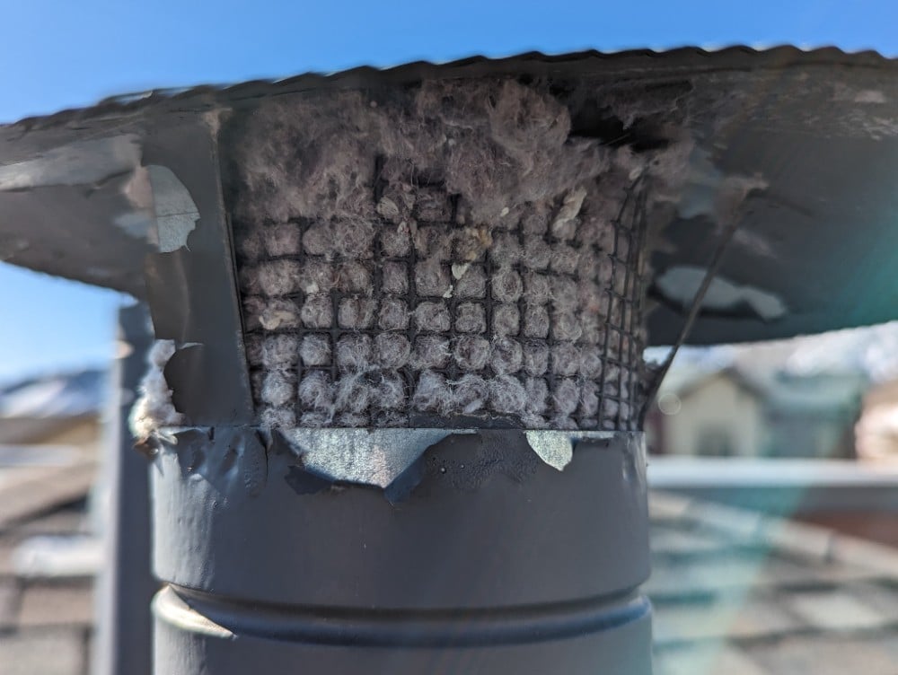 Close-up image showing debris-clogged roof vents at an assisted living facility in Golden, CO, with the Rocky Mountains in the background. The obstruction is caused by a vent screen