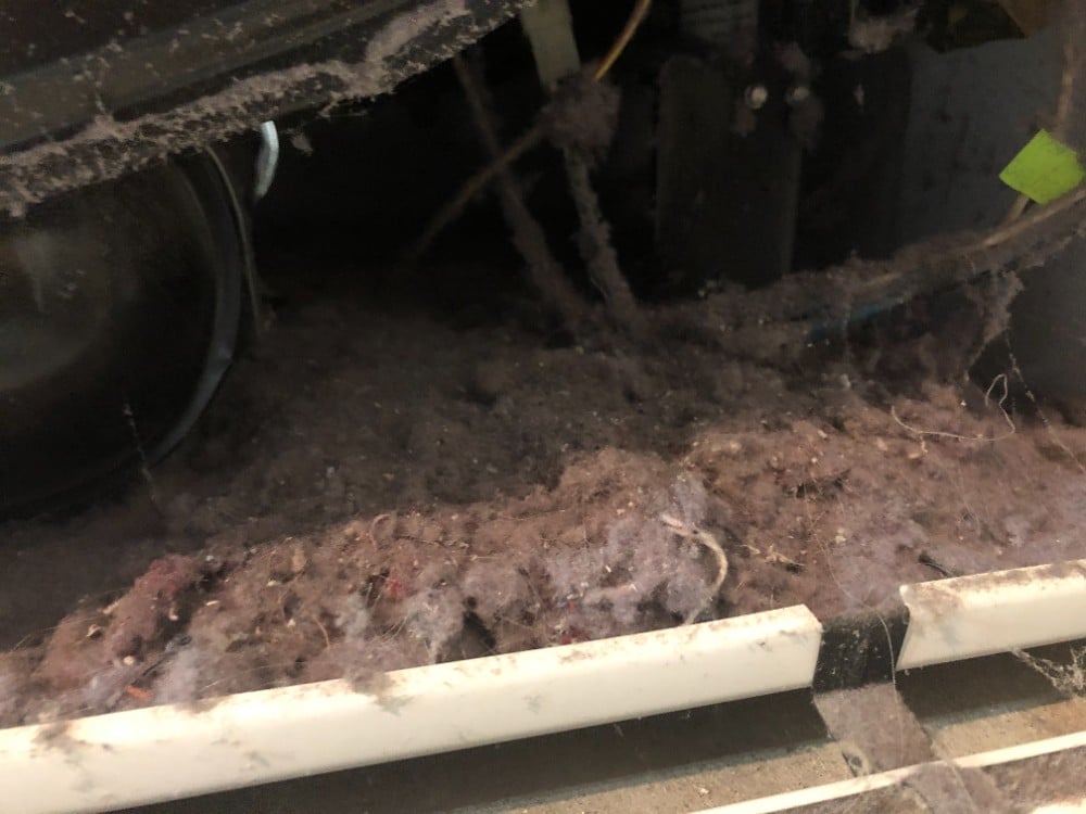 Lint build-up inside clothes dryer, prior to cleaning the dryer.