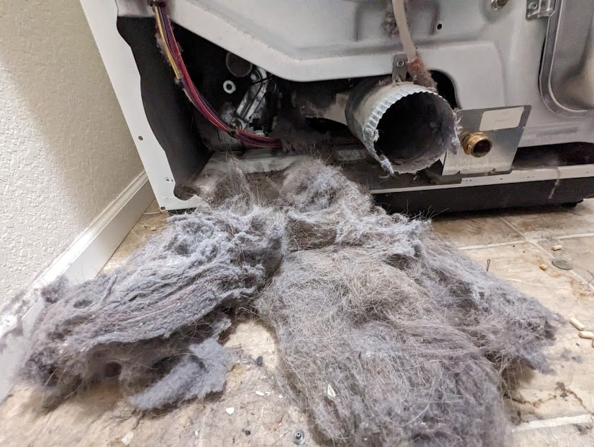 Removal of accumulated lint from the back of a dryer, highlighting essential maintenance performed in Boulder, CO