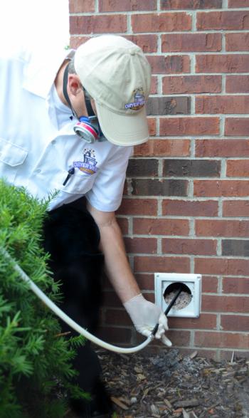 Dryer Vent Wizard technician cleaning an exterior vent