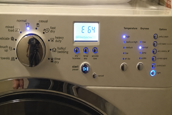 Close-up of a white dryer control panel with blue LED indicators, a cycle selection knob, and a digital display showing an E 64 error code message.