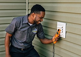Technician examining an outdoor dyer vent cover.