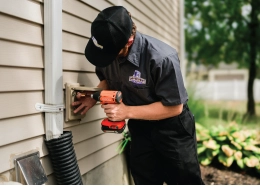 Technician examining an outdoor dyer vent cover with customer.