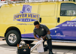 Technician kneeling in front of Dryer Vent Wizard van.